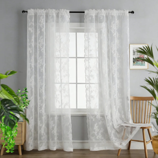 White vintage floral lace curtains hanging in a window with sheer white fabric.
