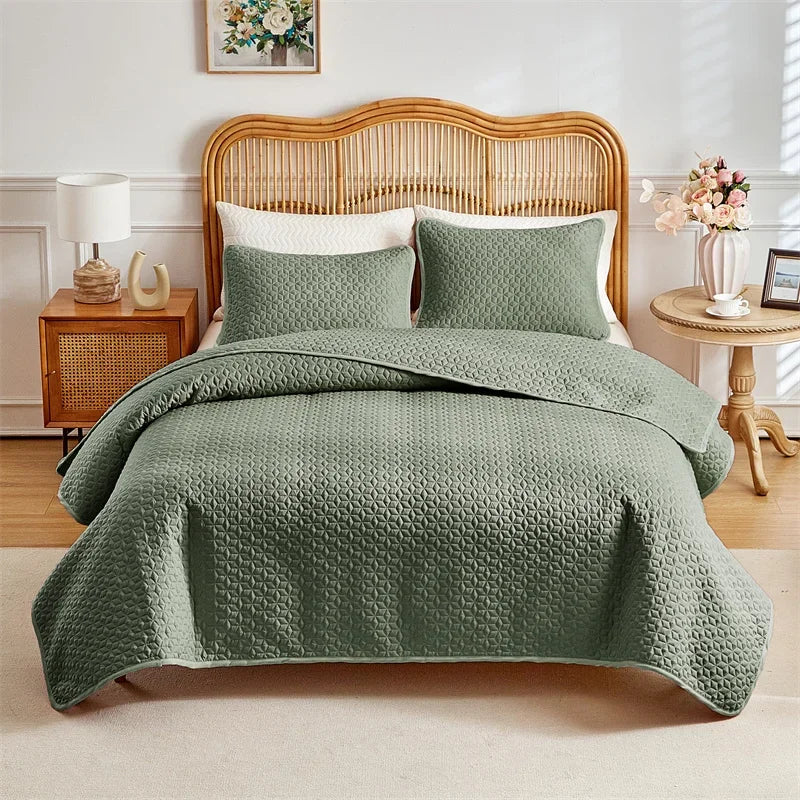 A green quilted duvet and pillow set displayed on a bed with a wooden headboard.
