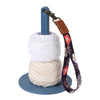 A white yarn holder with a blue rod and a brown leather strap featuring a floral pattern.