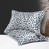 A set of two leopard print silk satin pillowcases with a black and white pattern displayed on a white surface.