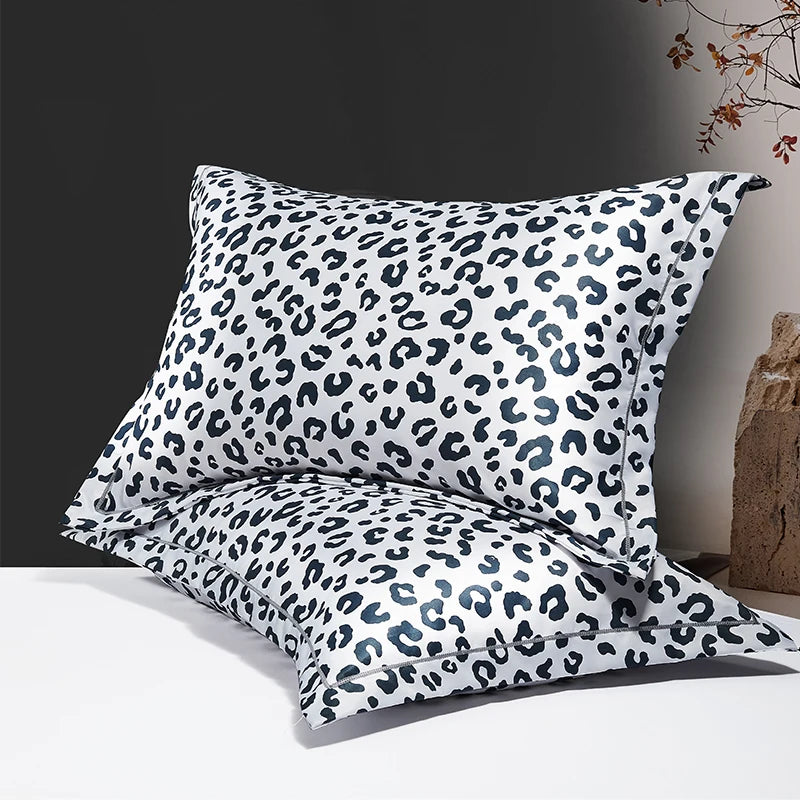 A set of two leopard print silk satin pillowcases with a black and white pattern displayed on a white surface.