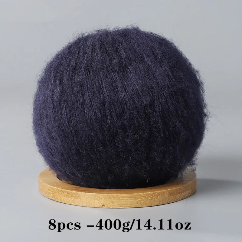 A ball of dark gray or black mohair yarn for crafting, resting on a wooden base.