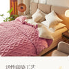 A pink quilted blanket is draped over a beige sofa next to a window with natural light.