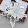 White floral applique fabric patch made of sheer lace and sequins displayed in a wooden frame.