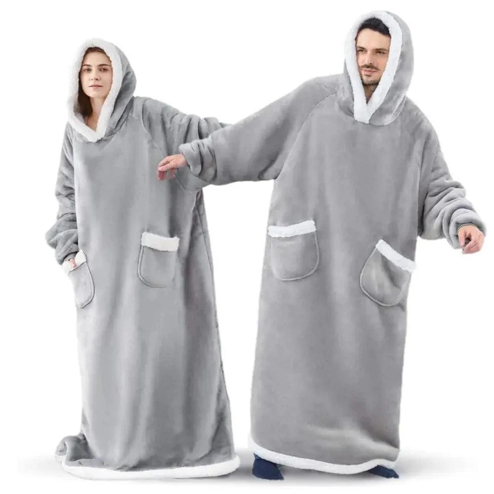 A man and a woman wearing oversized gray flannel blanket pyjama sets.