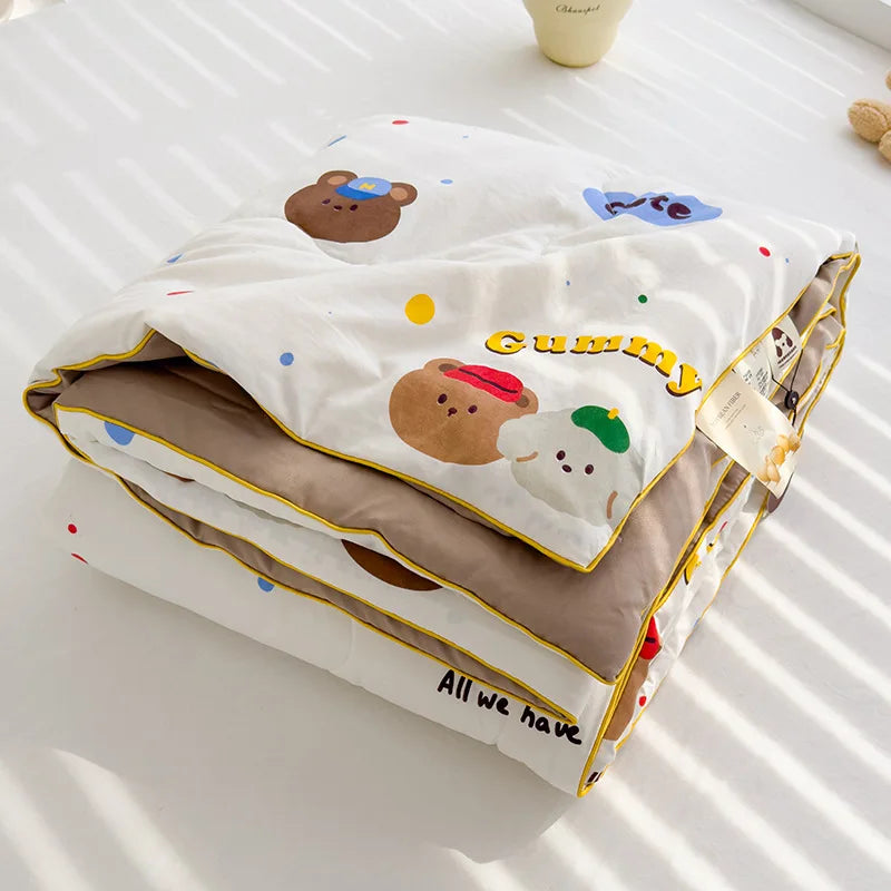 A white quilt featuring cute brown and white bear designs with the text Gummy All we have