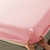 A close-up of a pink soft touch microfiber fitted sheet being held by hands.