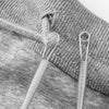 A close-up of a drawstring threader tool with a metal loop and spring, resting on a gray knitted fabric.