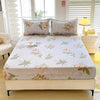 A fitted bed sheet with a floral print featuring soft greens and peach tones is displayed on a bed.