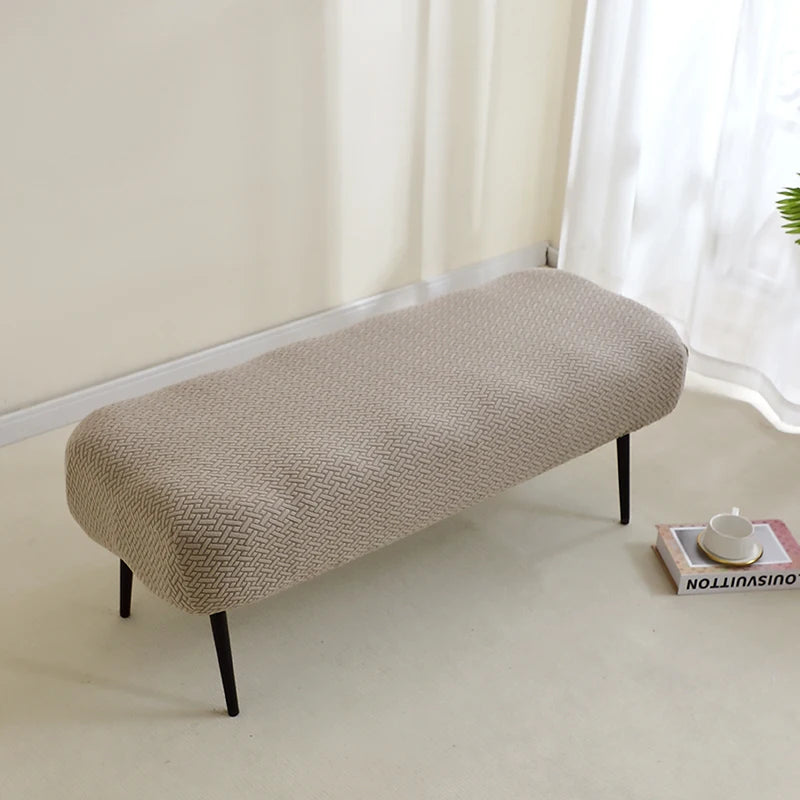 A beige elastic jacquard bench cover used as protection for a piano, dining, or entryway seat.