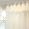 Sheer white double-layer curtains with a delicate lace overlay hanging from a rod.