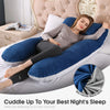 A woman is relaxing on a bed with a blue and gray U-shaped memory foam pillow for sleep.