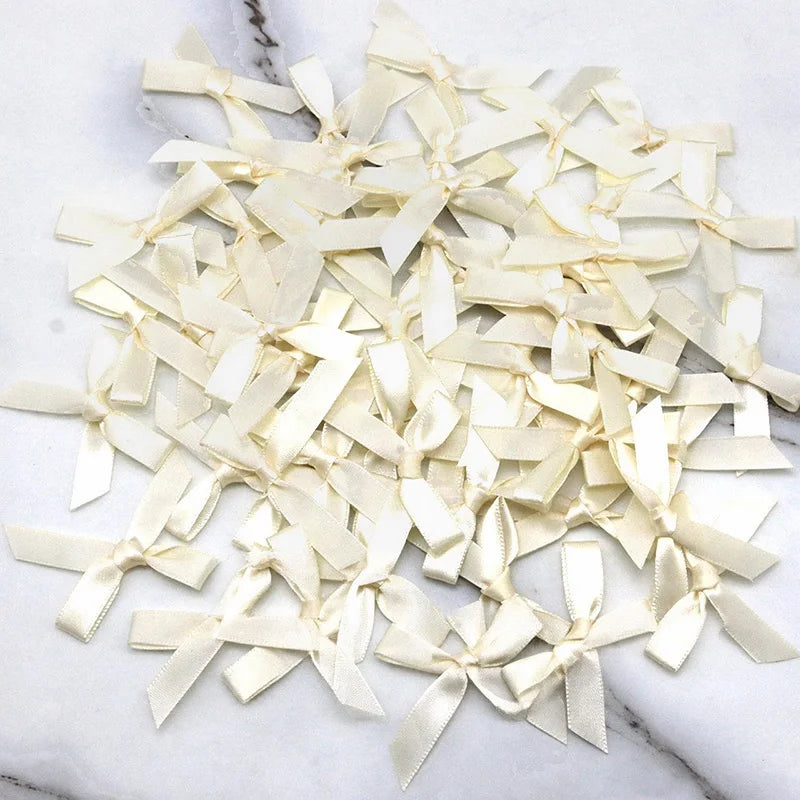 A pile of small, cream-colored satin ribbon bows for crafts and decor.