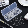 A transparent plastic box filled with round head push pins and a loose pack of similar pins on a dark surface.