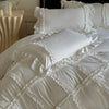 A white ruffled duvet cover set displayed on a bed with decorative pillows and candles.