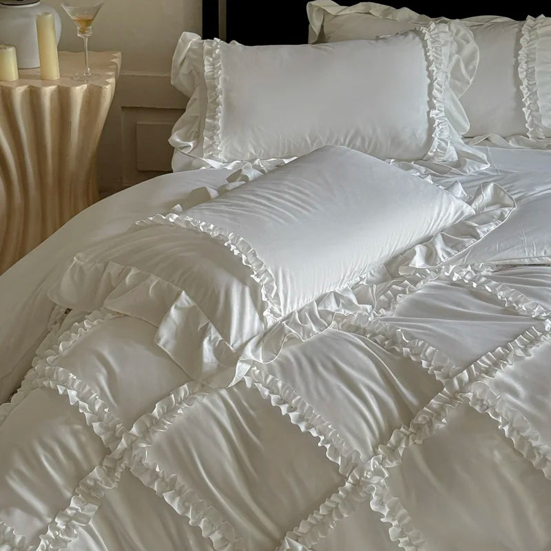 A white ruffled duvet cover set displayed on a bed with decorative pillows and candles.