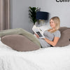 A woman is resting on a bed with an inflatable leg elevation pillow and storage bag, reading a book.
