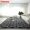 A dark gray geometric plush area rug placed on a light wooden floor in a bright living room.