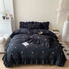 A black embroidered rose duvet cover set displayed on a bed with white and gray decor.