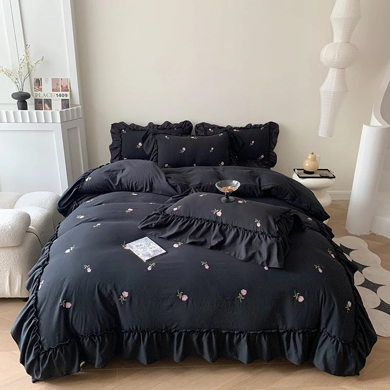 A black embroidered rose duvet cover set displayed on a bed with white and gray decor.