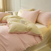 A soft pink and cream 3-piece duvet cover set with pillows on a bed.