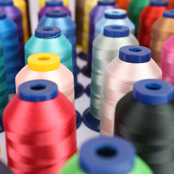 A close-up view of various spools of high-quality polyester embroidery thread in multiple colors and shades.