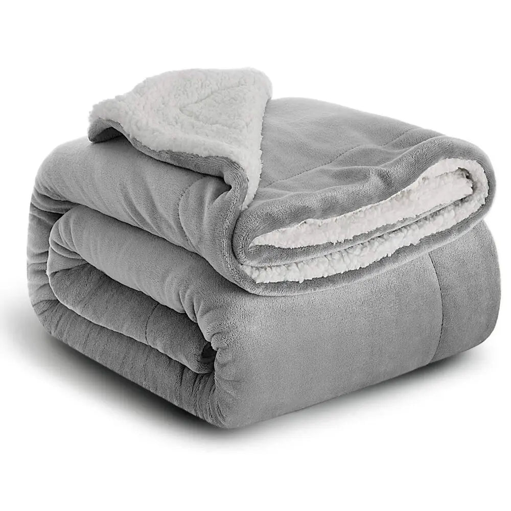 A folded gray sherpa fleece blanket with a white fluffy trim.