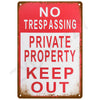 A vintage red and white metal sign with the text NO TRESPASSING PRIVATE PROPERTY KEEP OUT.