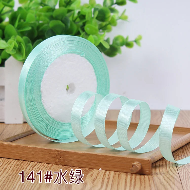 Roll of light mint green satin ribbon with a white center core