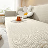 A light beige jacquard sofa cover with white decorative pillows and an orange mug on a modern sofa.