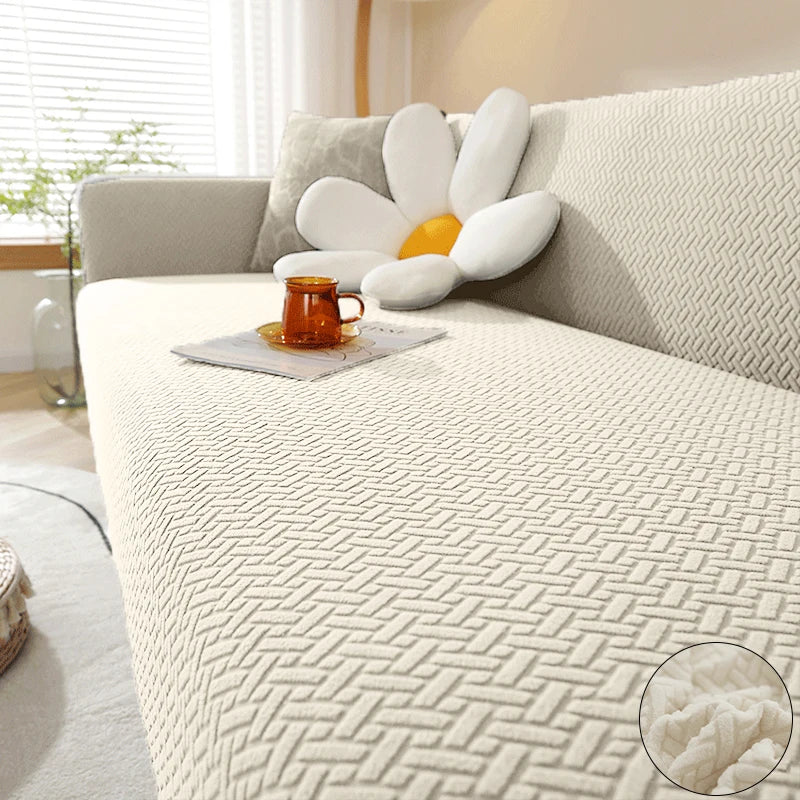 A light beige jacquard sofa cover with white decorative pillows and an orange mug on a modern sofa.
