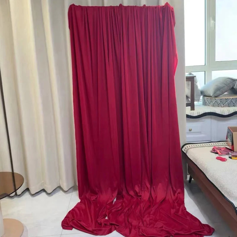 A floor-length drape of vibrant red stretch fabric hanging in a bright room.