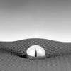 Close-up view of a silver metal object embedded in a dark, textured non-slip door mat.