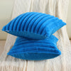 A bright blue faux rabbit fur cushion cover resting on a white textured fabric.