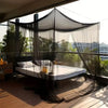 A large four-door mosquito net draped over a bed on an outdoor balcony.