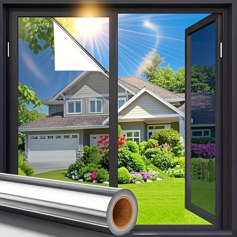 A close-up view of a reflective mirror window film installed in a window, showing sunlight and a residential house.