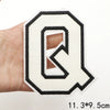 A white letter Q patch with a black outline is held in a hand.