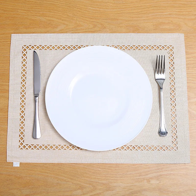 A white dinner plate, knife, and fork are placed on a natural linen placemat on a wooden table.