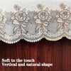 Close-up of a sheer white lace trim with floral embroidery on a dark wooden surface.