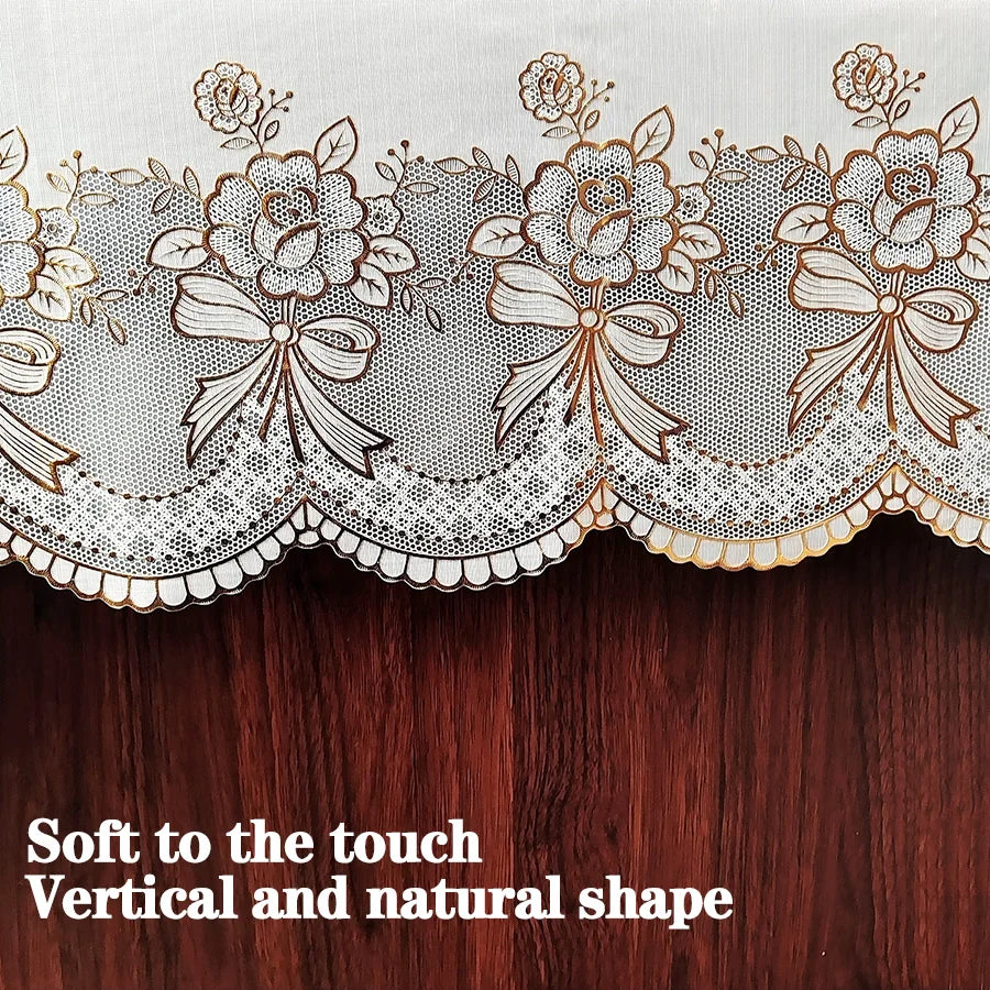 Close-up of a sheer white lace trim with floral embroidery on a dark wooden surface.