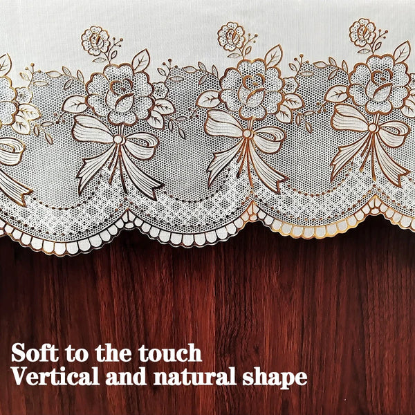 Close-up of a sheer white lace trim with floral embroidery on a dark wooden surface.
