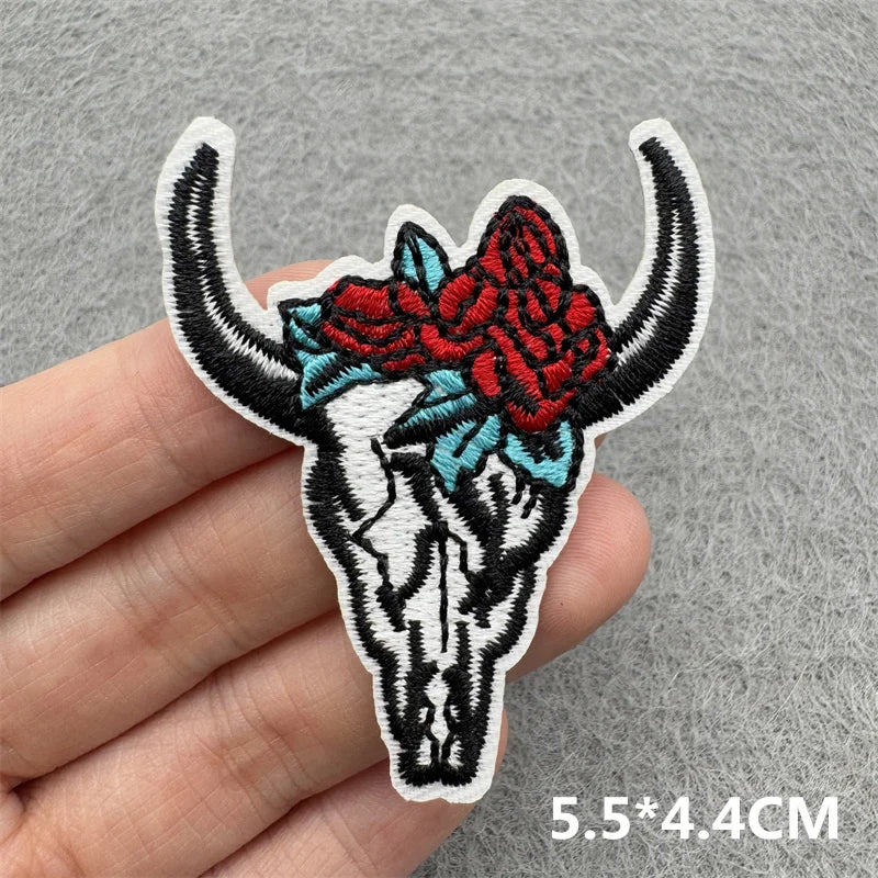Black and white embroidered iron-on patch of a bull skull with red and blue floral accents