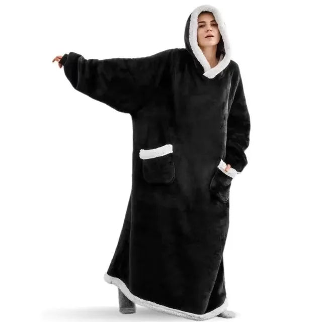 A person wearing an oversized black flannel blanket pyjama set with a hood.