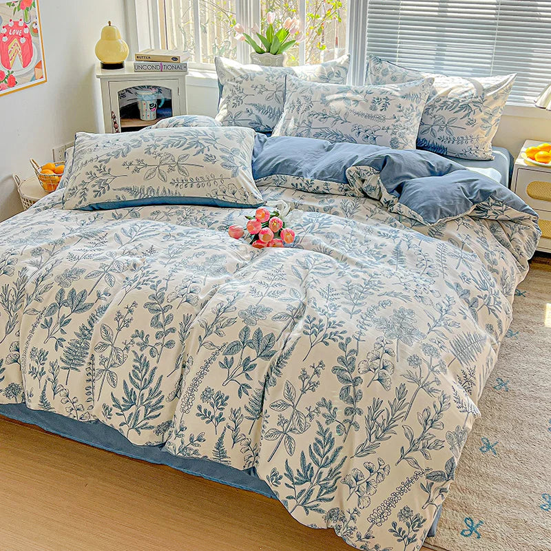 A floral printed bedding set featuring blue and white patterns on a bed with sheer white blinds.
