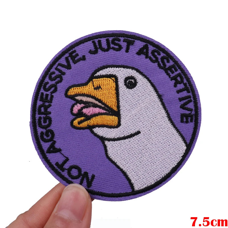 Purple embroidered patch featuring a white duck with text reading Not Aggressive Just Assertive