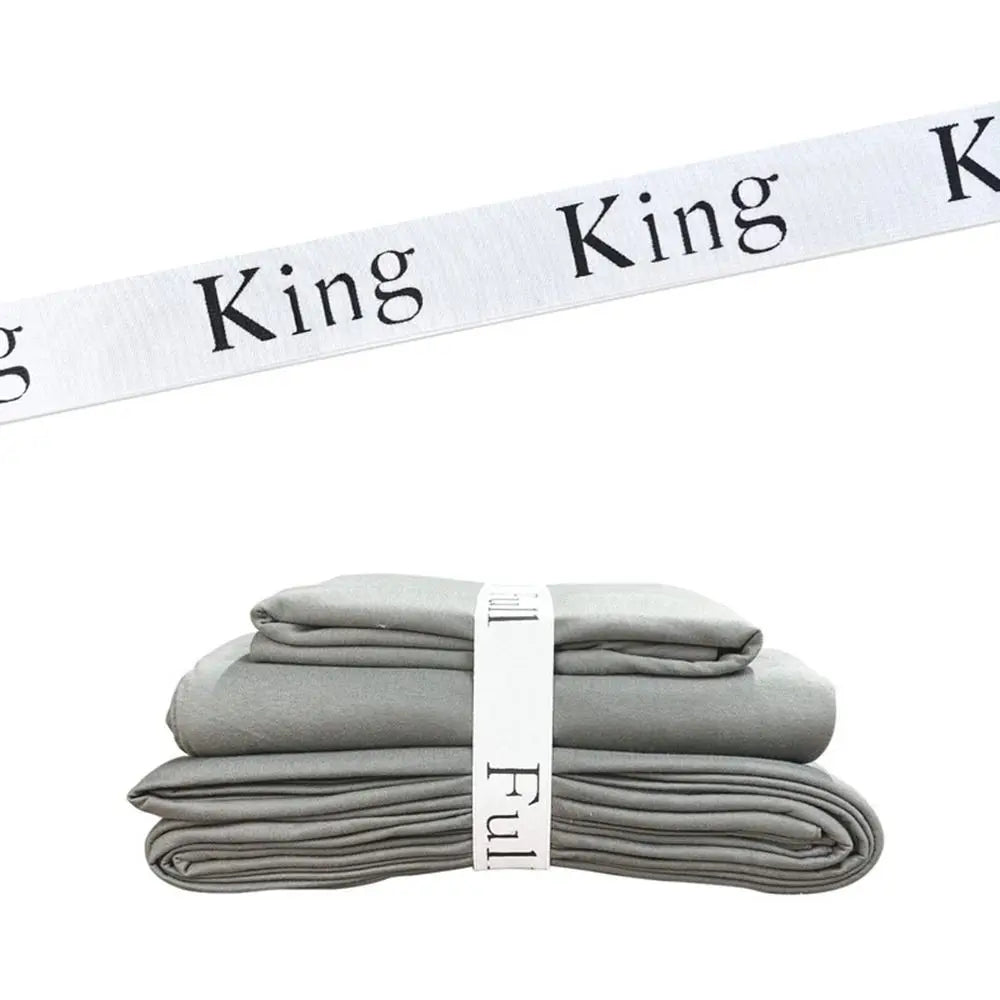 A stack of gray bed sheets rolled and secured with white King straps.