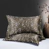 A pair of leopard print silk satin pillowcases displayed on a white surface against a dark gray background.