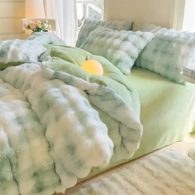 A light green duvet cover with white and blue patterned fleece throws and pillows on a bed.