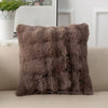 A plush faux rabbit fur decorative throw pillow in a warm brown color resting on a light-colored sofa.