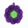 A purple, fuzzy flower-shaped kitchen dish scrubber sponge with a bright green center.